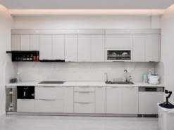 Tủ bếp inox cánh kính hiện đại tích hợp tủ lạnh side by side và hệ tủ kịch trần giúp tối ưu công năng sử dụng cho không gian bếp hiện đại.